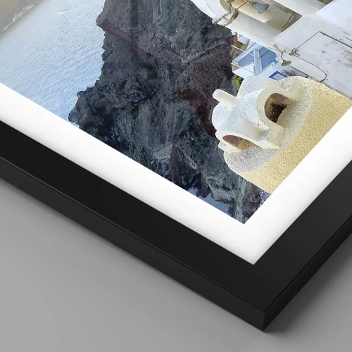 Poster in een zwarte lijst - Santorini - genesteld tegen de rotsen - 40x30 cm