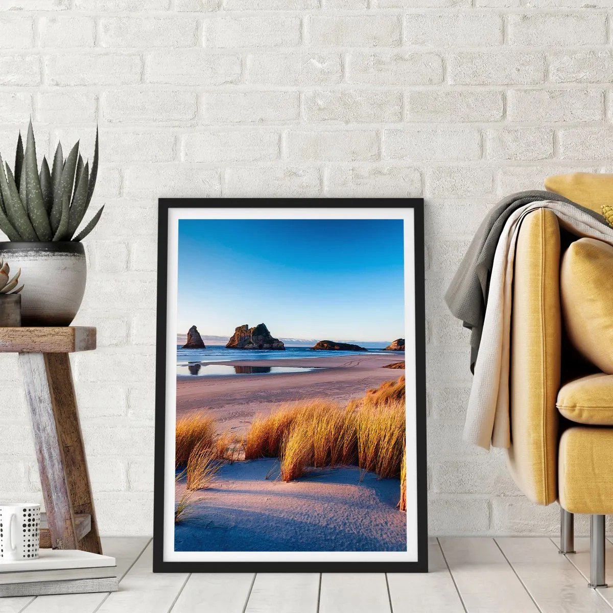 Poster in een zwarte lijst - Een pittoresk strand met gras en rotsen tegen de achtergrond van een kalme oceaan - 50x70cm - Voor rustzoekers - Moderne wanddecoratie voor woonkamer en slaapkamer ARTTOR