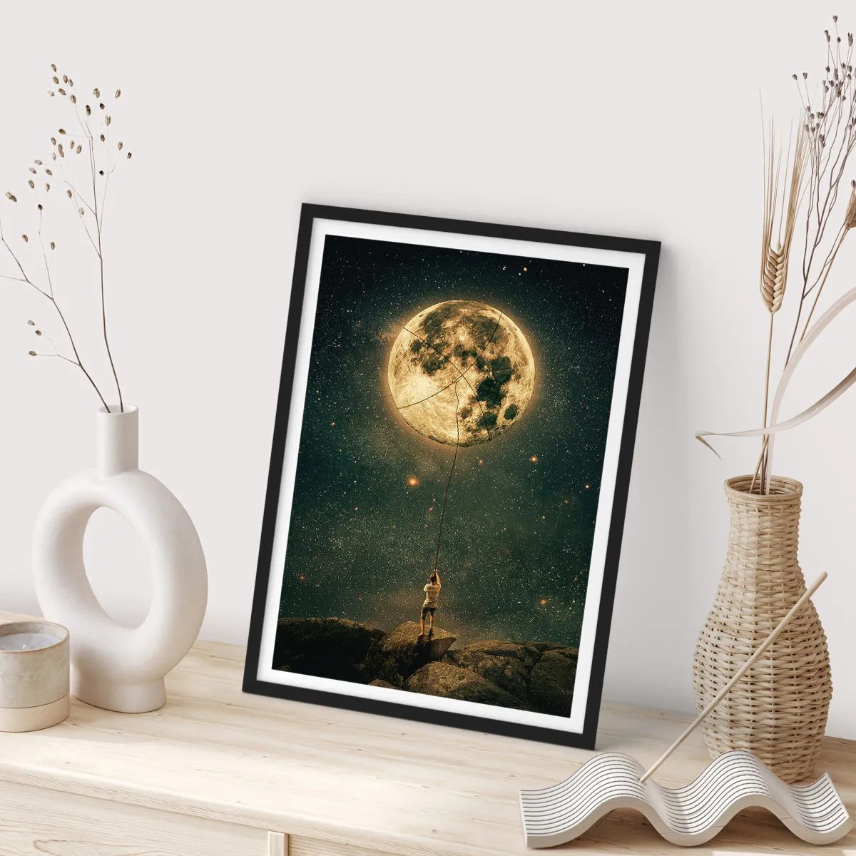 Poster in een zwarte lijst - Een figuur houdt de maan aan een touw vast in een sterrenlandschap. - 50x70cm - Iemand die de maan heeft gestolen - Moderne wanddecoratie voor woonkamer en slaapkamer ARTTOR